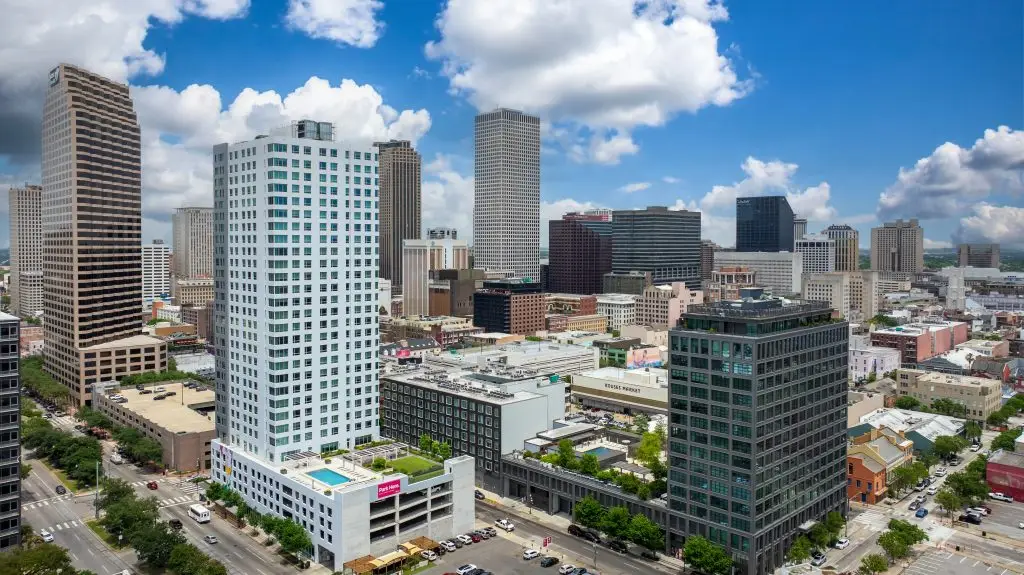 Downtown skyline with tall office buildings under a blue sky with fluffy clouds, viewed from above street level.